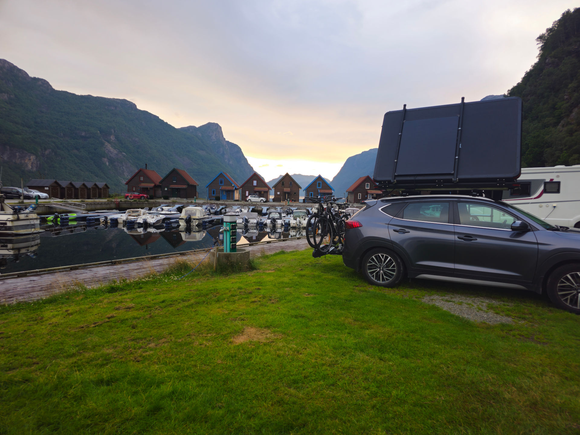 The SUV with the rooftop tent and solar panel parked at a scenic campsite.