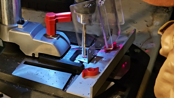 Drilling holes in a metal flat bar for the mounting bracket.